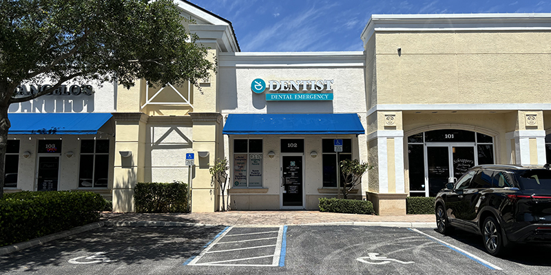 The image is a photograph of a commercial building with a sign that reads 'Dentist,' situated in a parking lot.