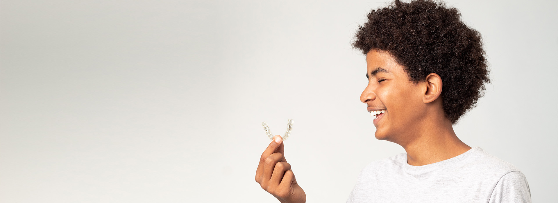 The image features a young person holding a flower in their hand, smiling at the camera.